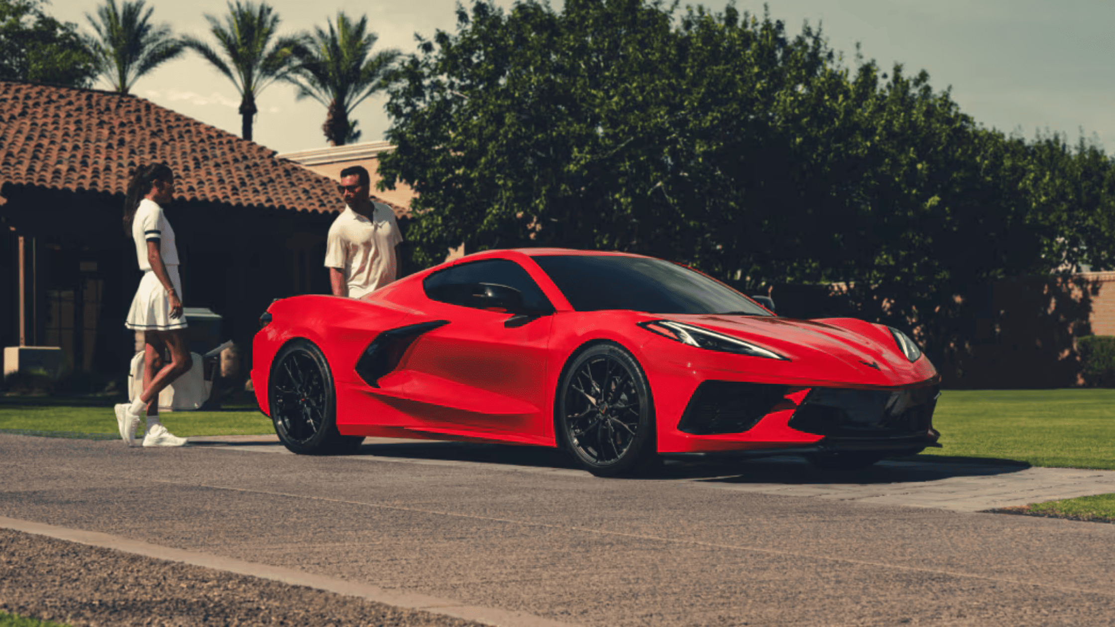 2025 Chevrolet Corvette Stingray parked in front of a home with two people nearby