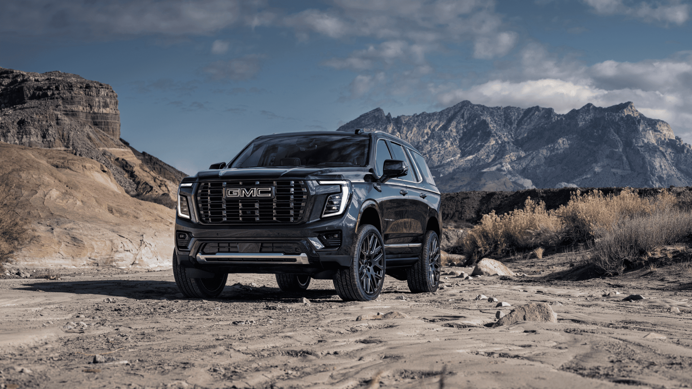 2025 GMC Yukon XL parked on rugged terrain with mountains in the distance