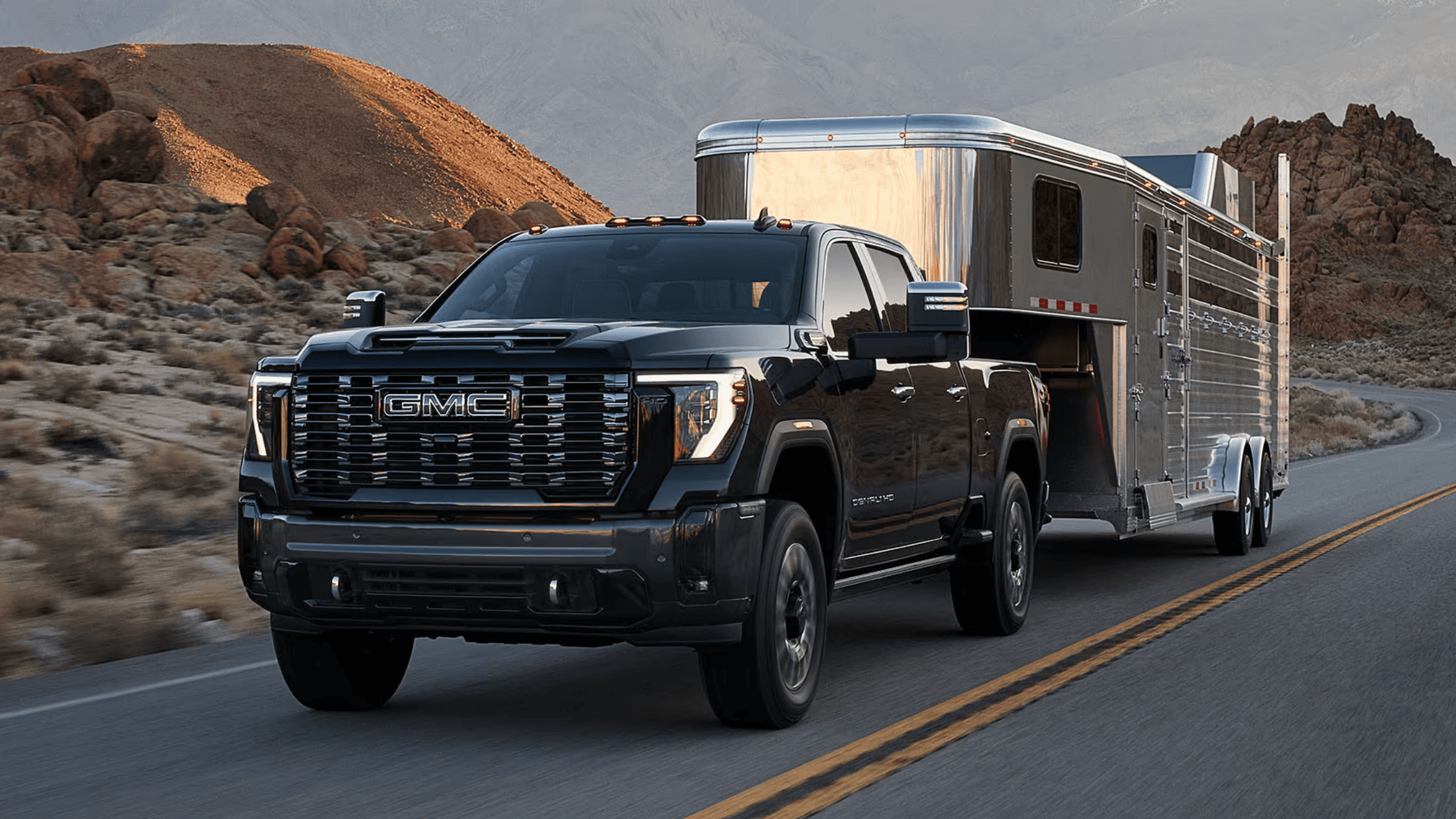2025 GMC Sierra 2500 HD towing a large trailer through a desert mountain road