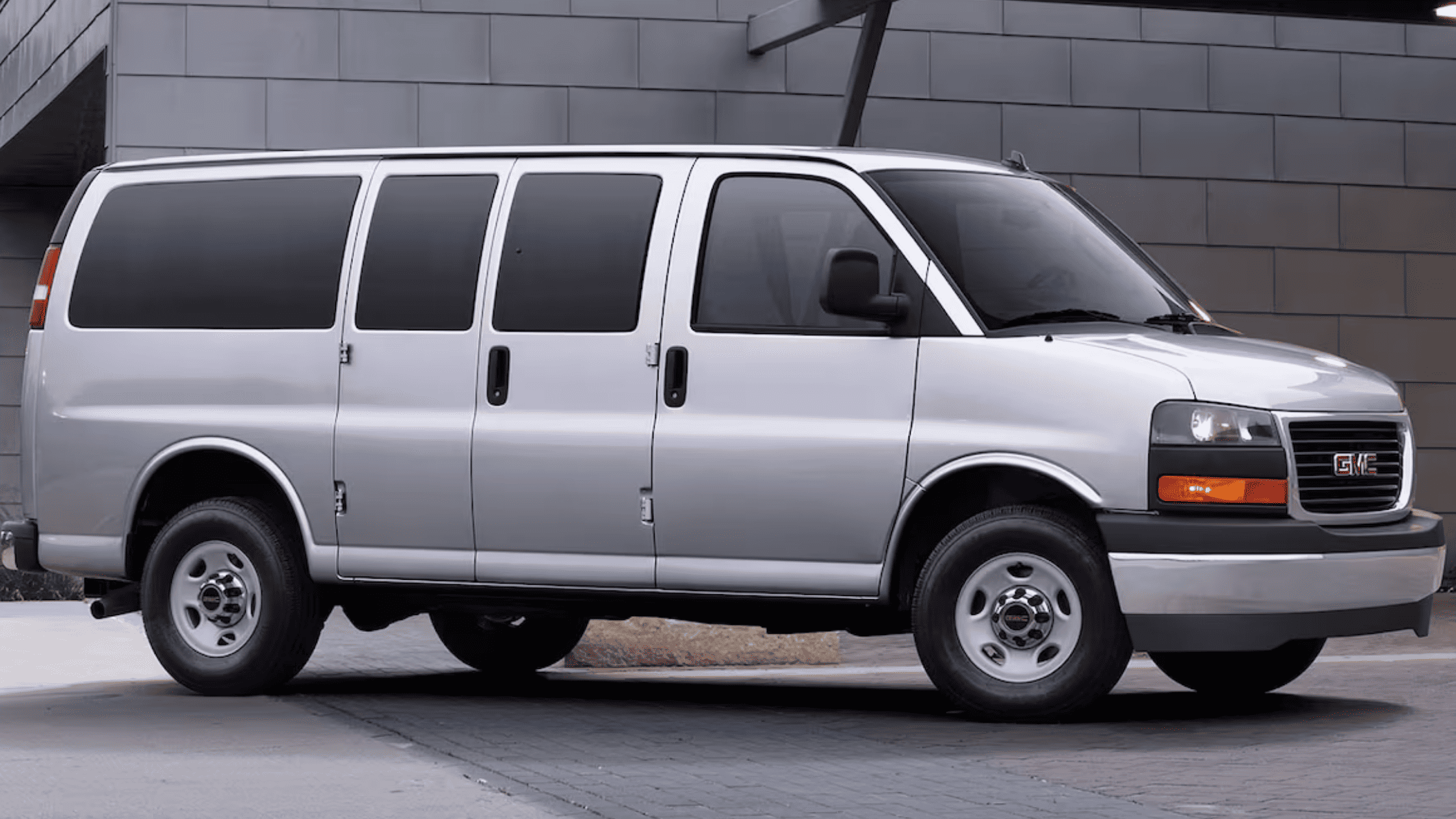Side view of the 2025 GMC Savana Passenger Van parked in a modern setting near West Jefferson, NC, highlighting its practical fleet-ready design.