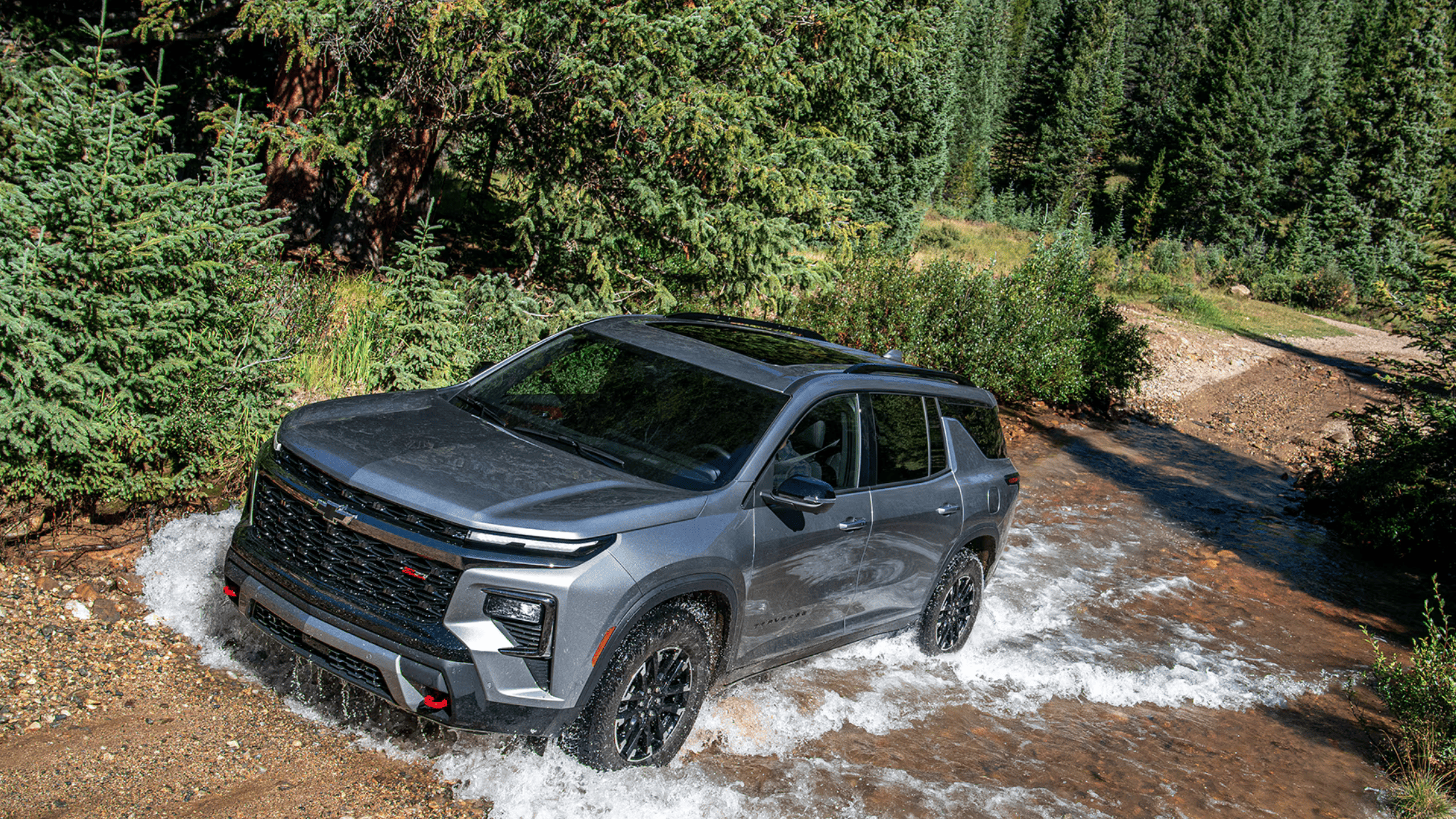 2025 Chevrolet Traverse driving through a shallow creek surrounded by lush greenery near West Jefferson, NC.
