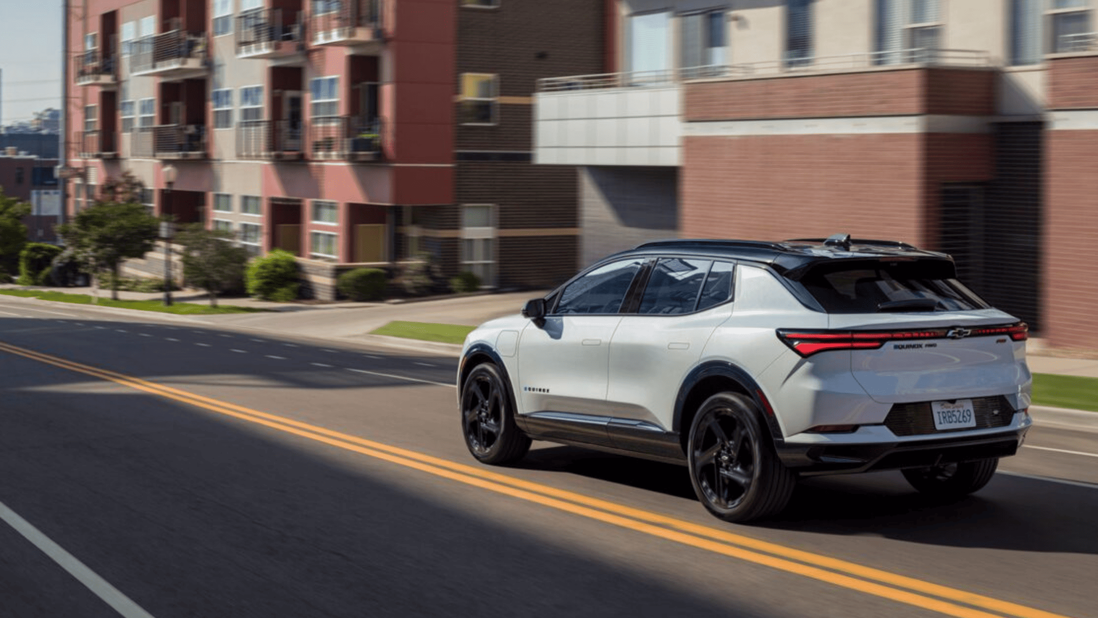 2025 Chevrolet Equinox in white driving through a suburban neighborhood in Morganton, NC, emphasizing its modern crossover styling and everyday comfort.