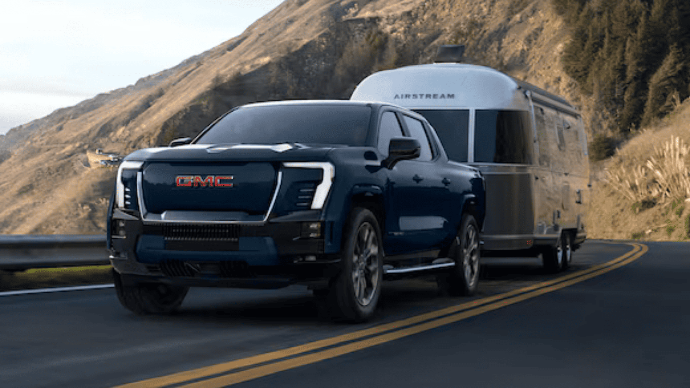 2026 GMC Sierra EV towing an Airstream trailer through mountain roads near Morganton NC.