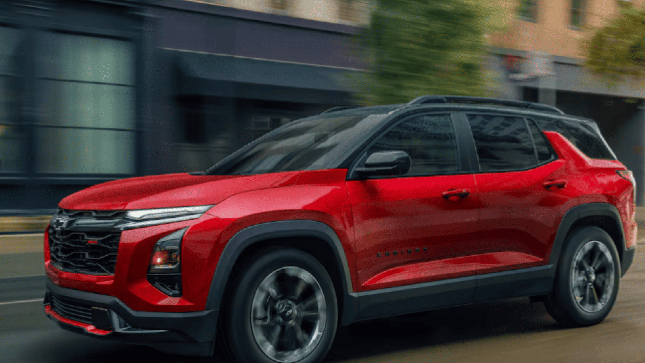 2026 Chevrolet Equinox in red driving through the city, highlighting its compact SUV design for Morganton NC drivers.