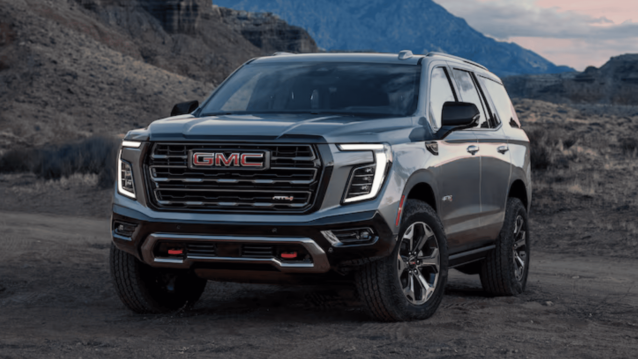 2026 GMC Yukon parked on rugged terrain, highlighting bold front grille, LED headlights, and advanced safety features for family travel near Morganton, NC.
