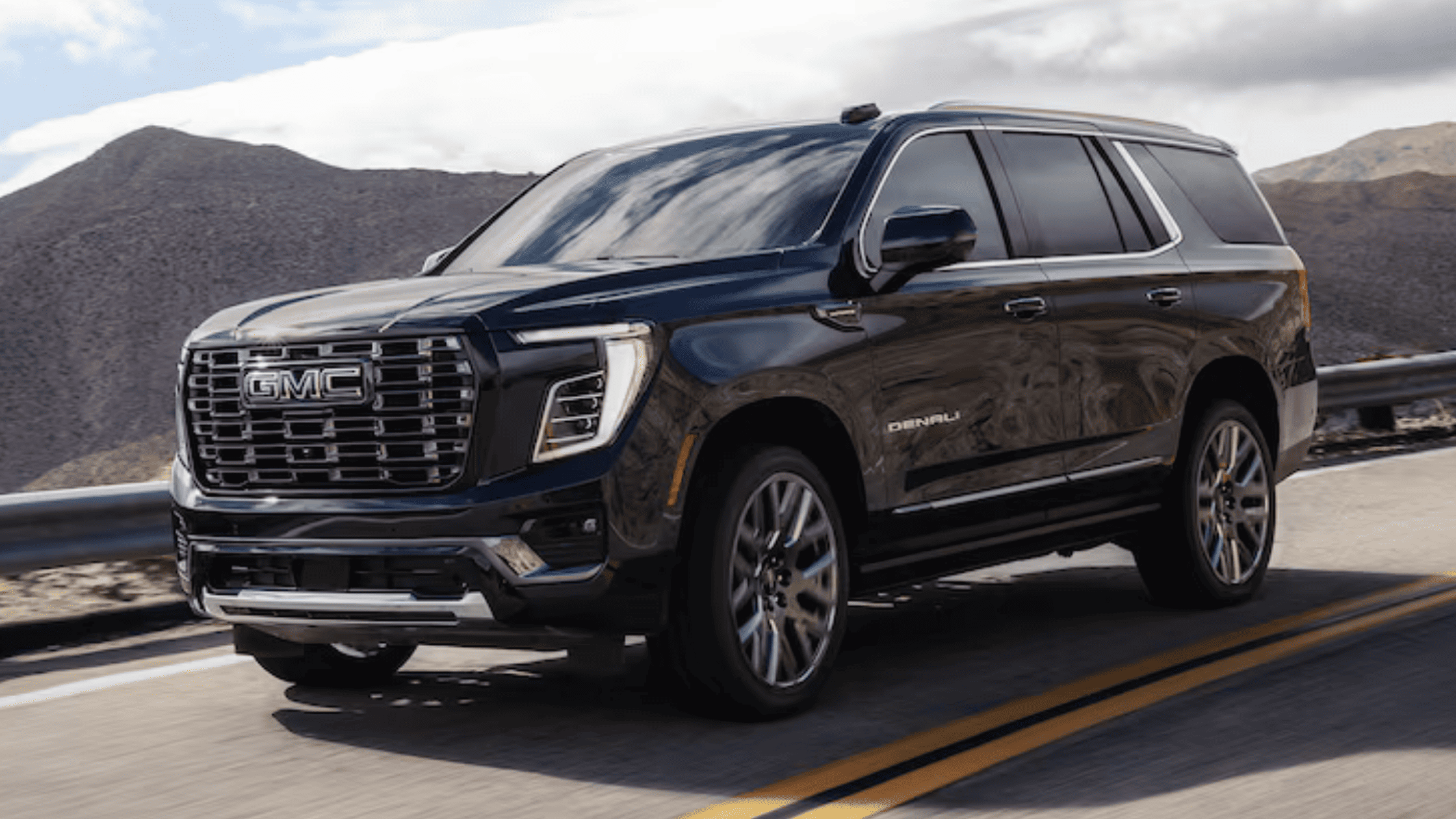 2026 GMC Yukon XL driving on a mountain highway, showcasing extended body size, spacious interior, and premium SUV comfort near Morganton, NC.