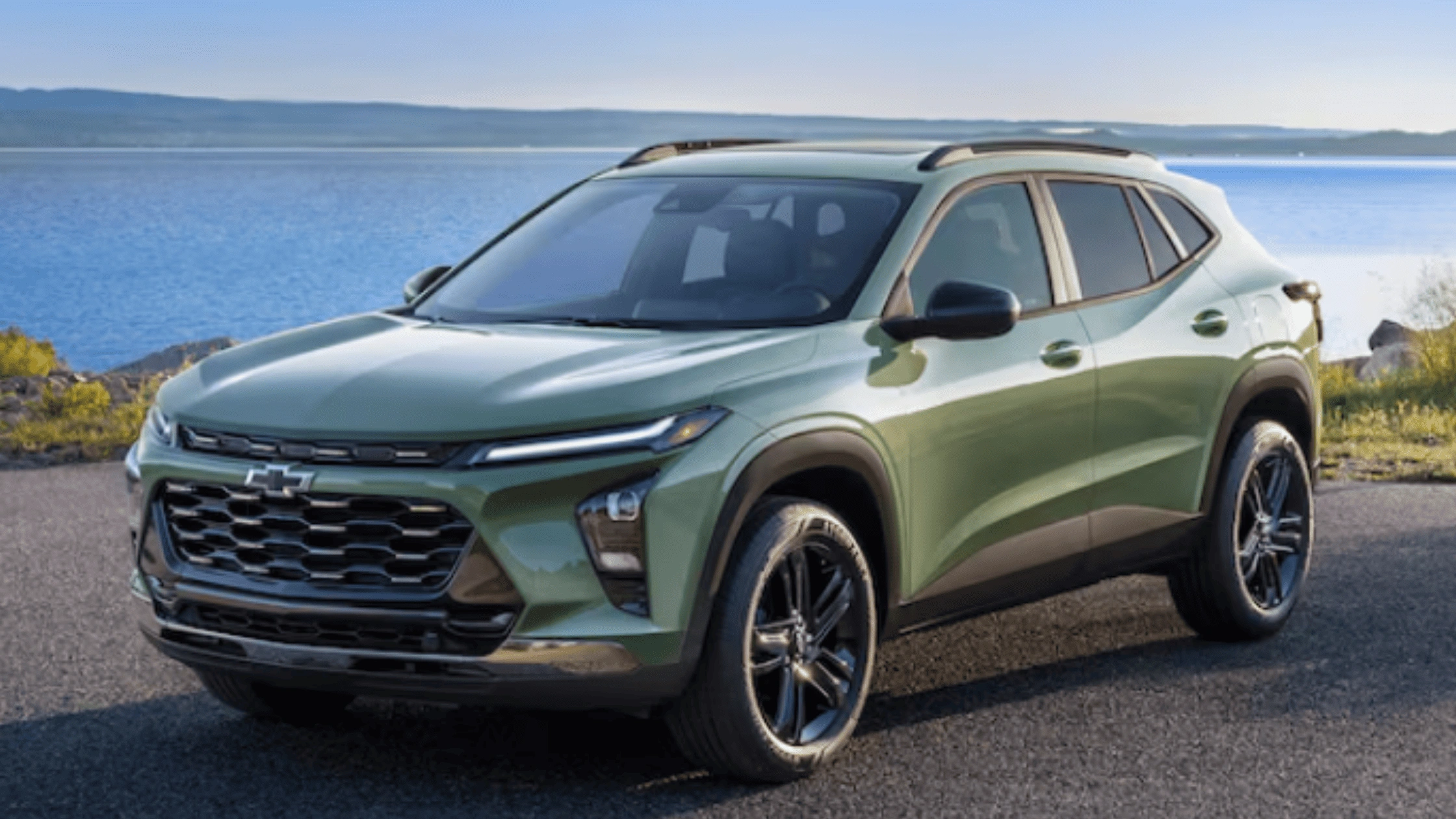 Green 2026 Chevrolet Trax compact SUV parked near a scenic lake, highlighting family-friendly design and versatility near Boone, NC.