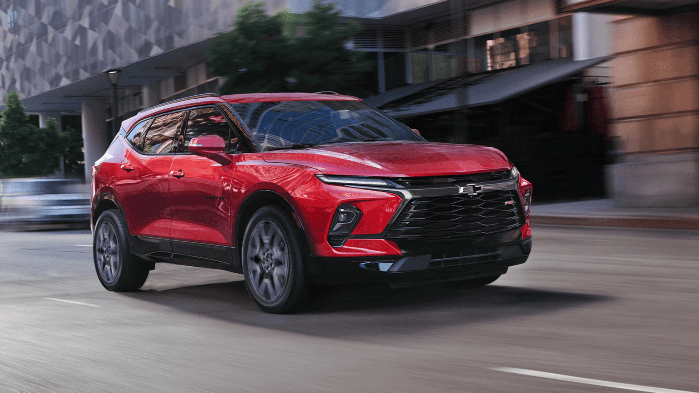 2026 Chevrolet Blazer RS midsize SUV in red with black wheels driving through urban city street in Boone NC