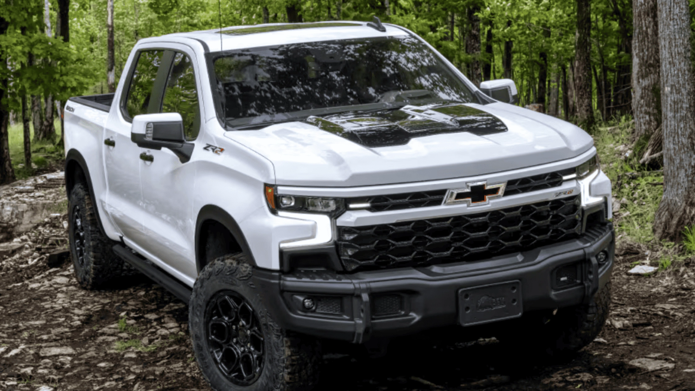 2026 Chevrolet Silverado ZR2 off-road pickup truck in white with black lifted suspension and all-terrain tires on rocky forest trail in Boone NC