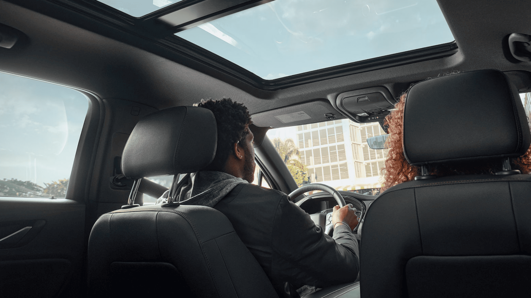 Driver and passenger inside Chevrolet Blazer with open panoramic sunroof.