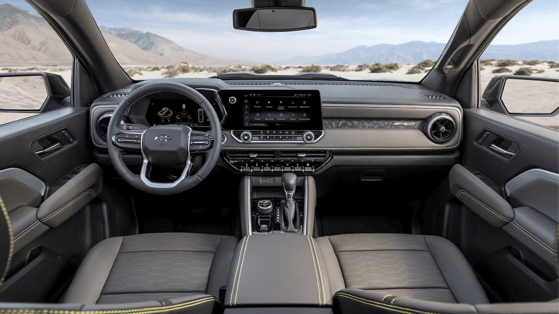 Chevrolet Colorado parked on a rugged hilltop with mountain views at sunset.