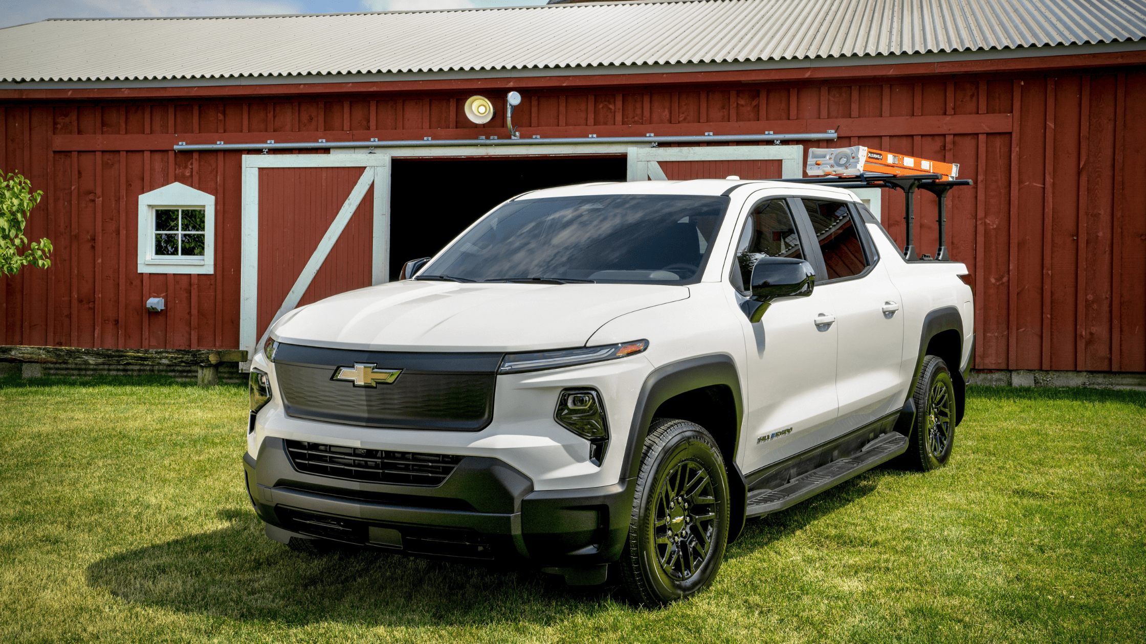 2024 Silverado EV parked in front of a red barn with a ladder mounted on top.
