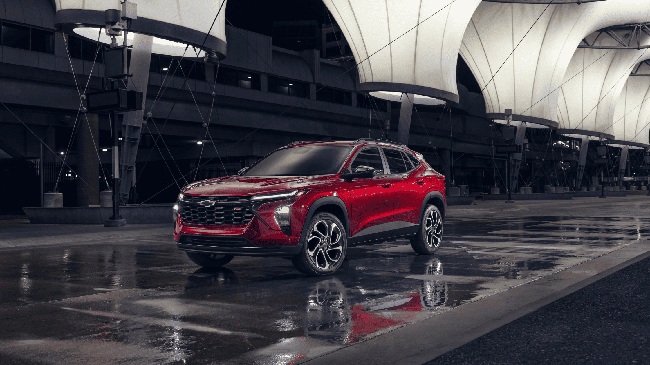 2025 Chevrolet Trax RS in red parked on wet pavement under illuminated canopy structure