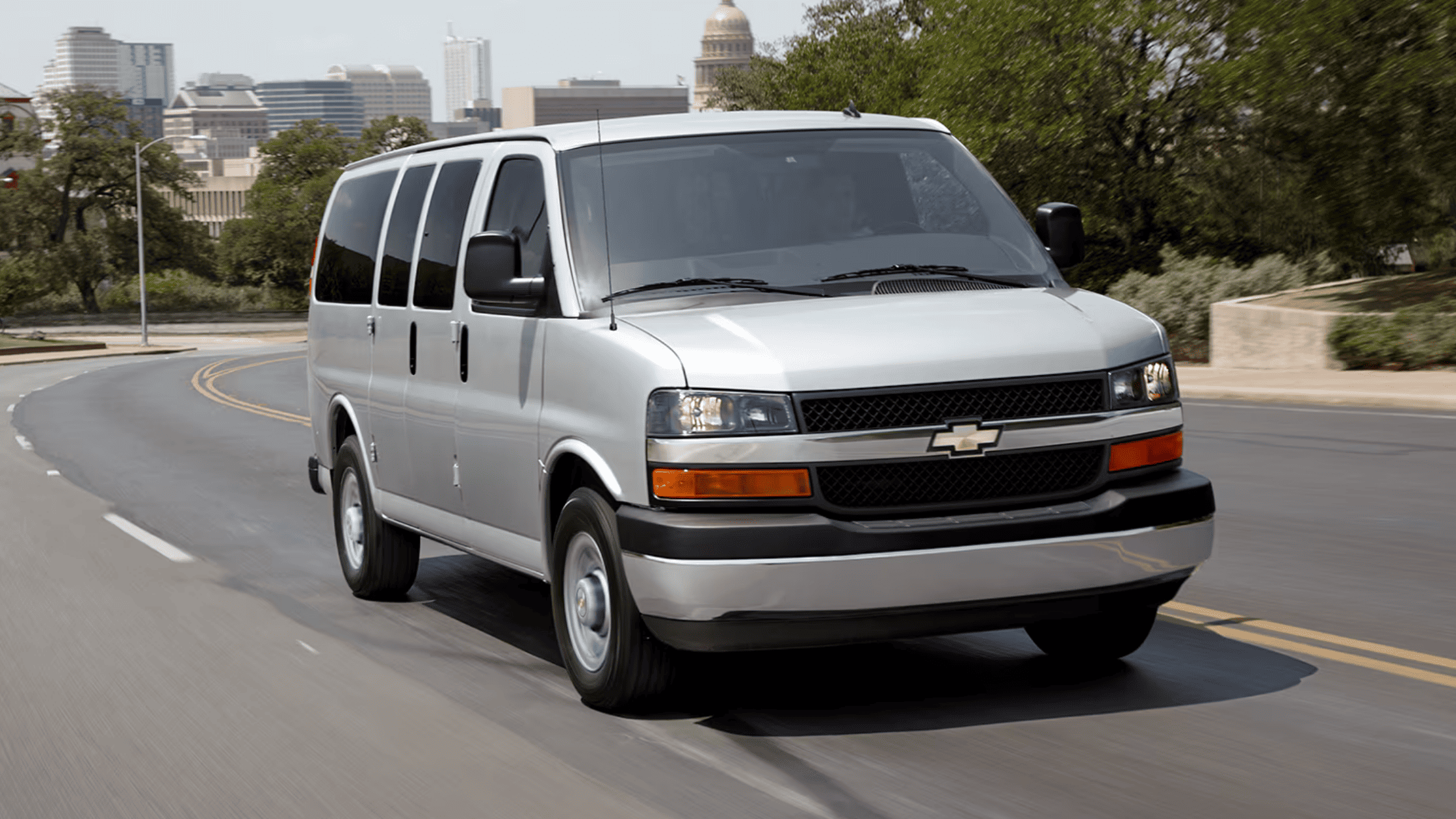 Silver Chevrolet Express van driving on a city road