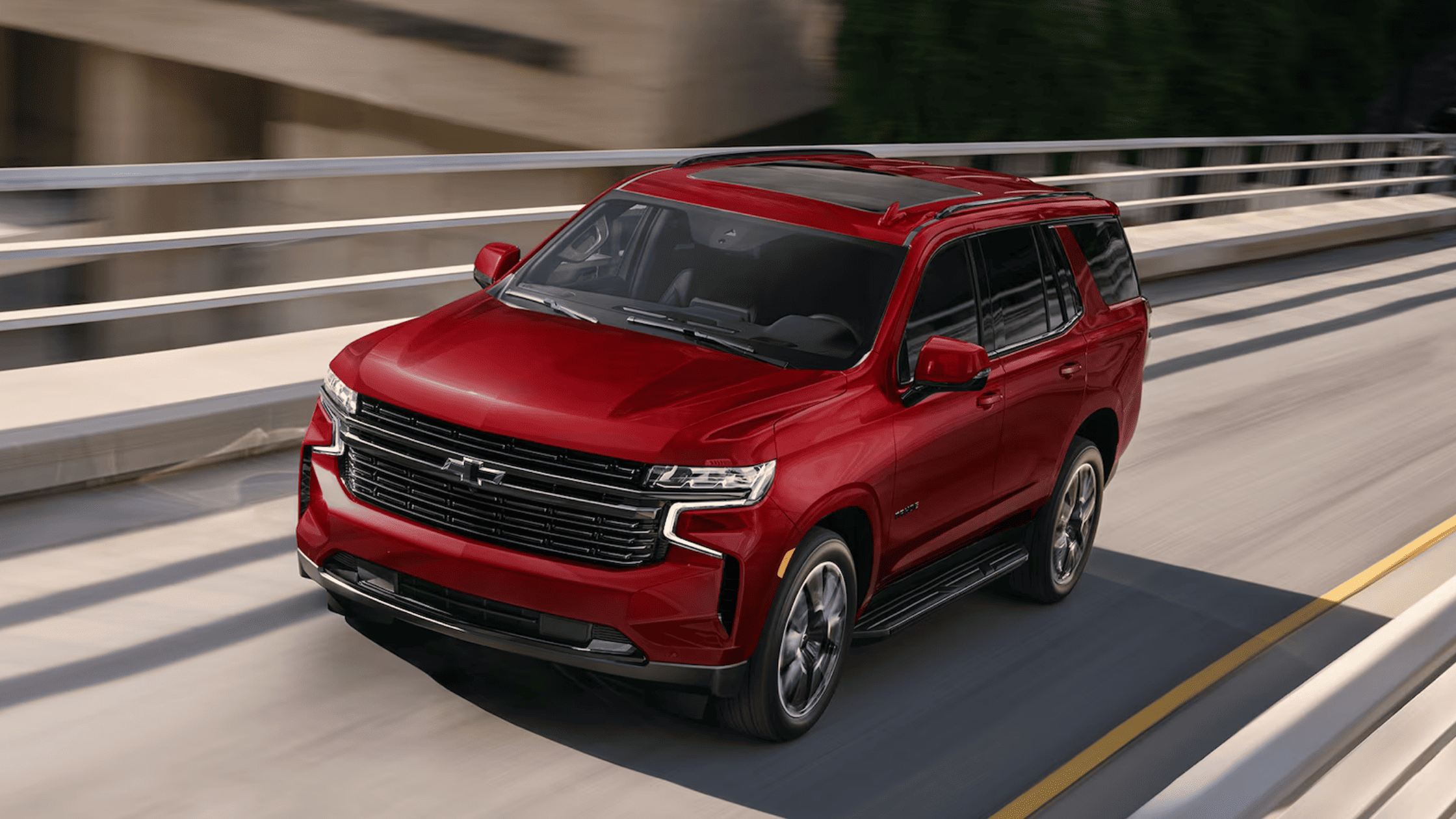 2024 Chevrolet Tahoe in red driving on a modern city highway