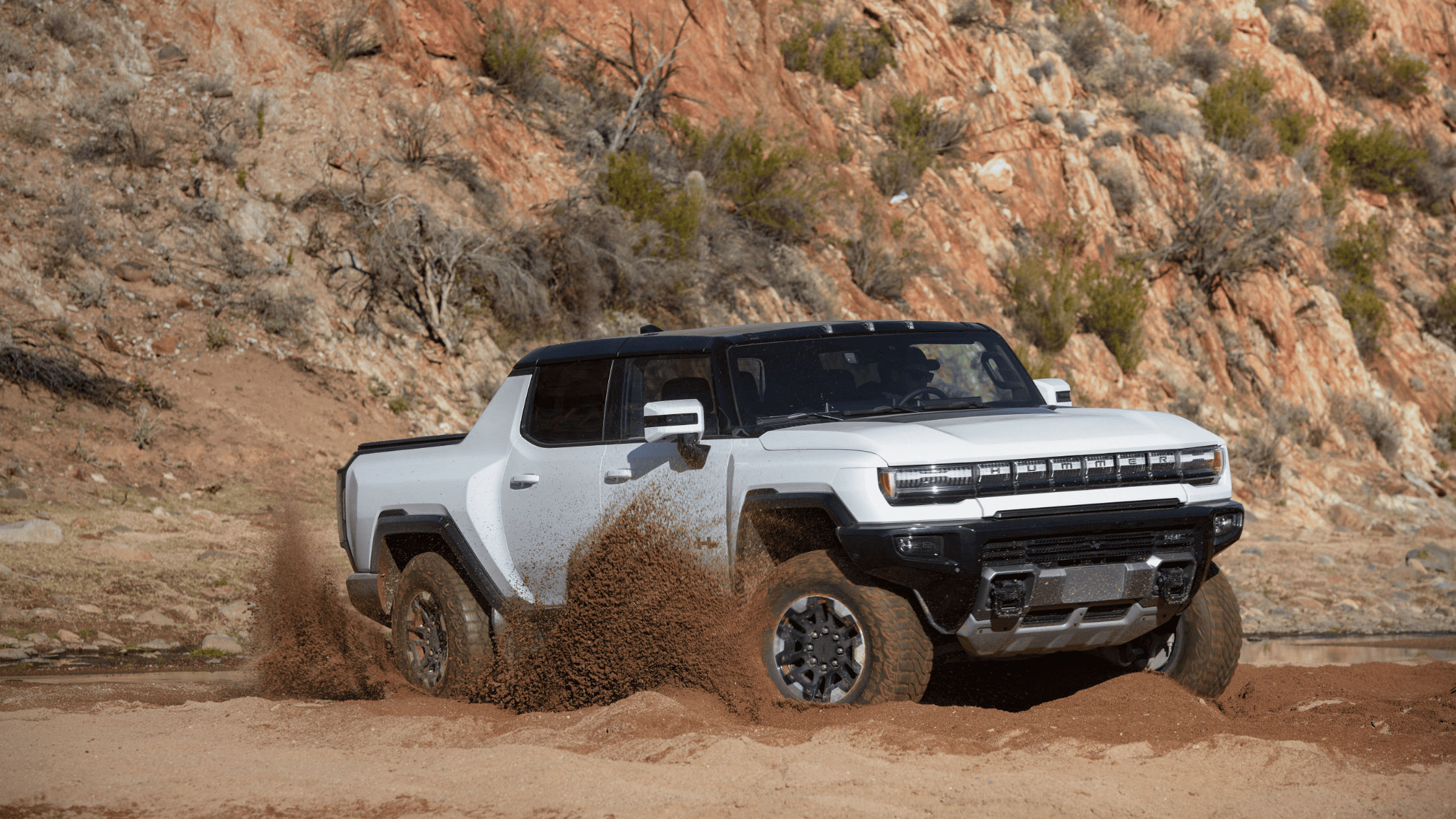 GMC Hummer EV Pickup tackling desert terrain, with front wheels turned.