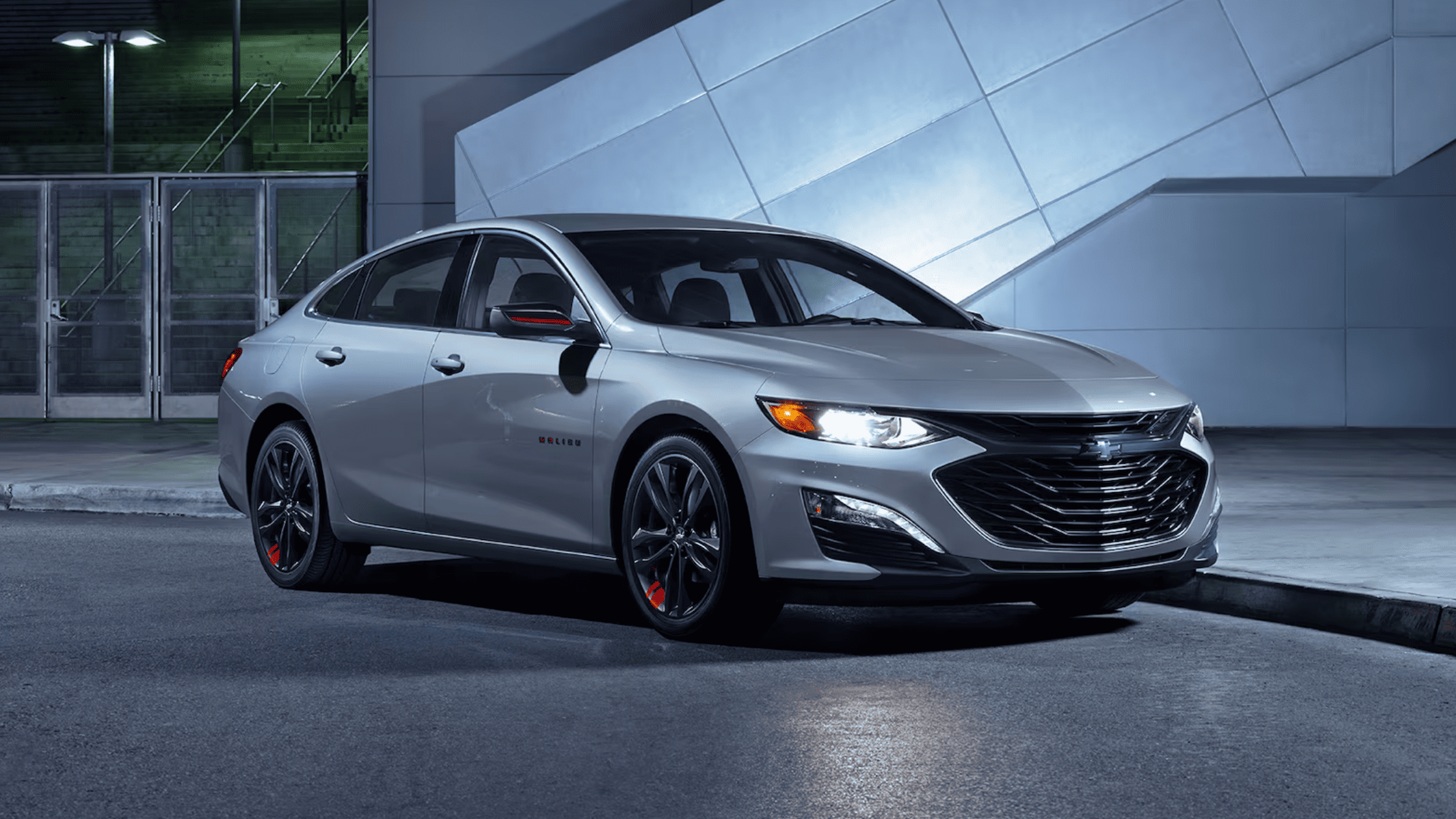2024 Chevrolet Malibu parked at night near modern architecture
