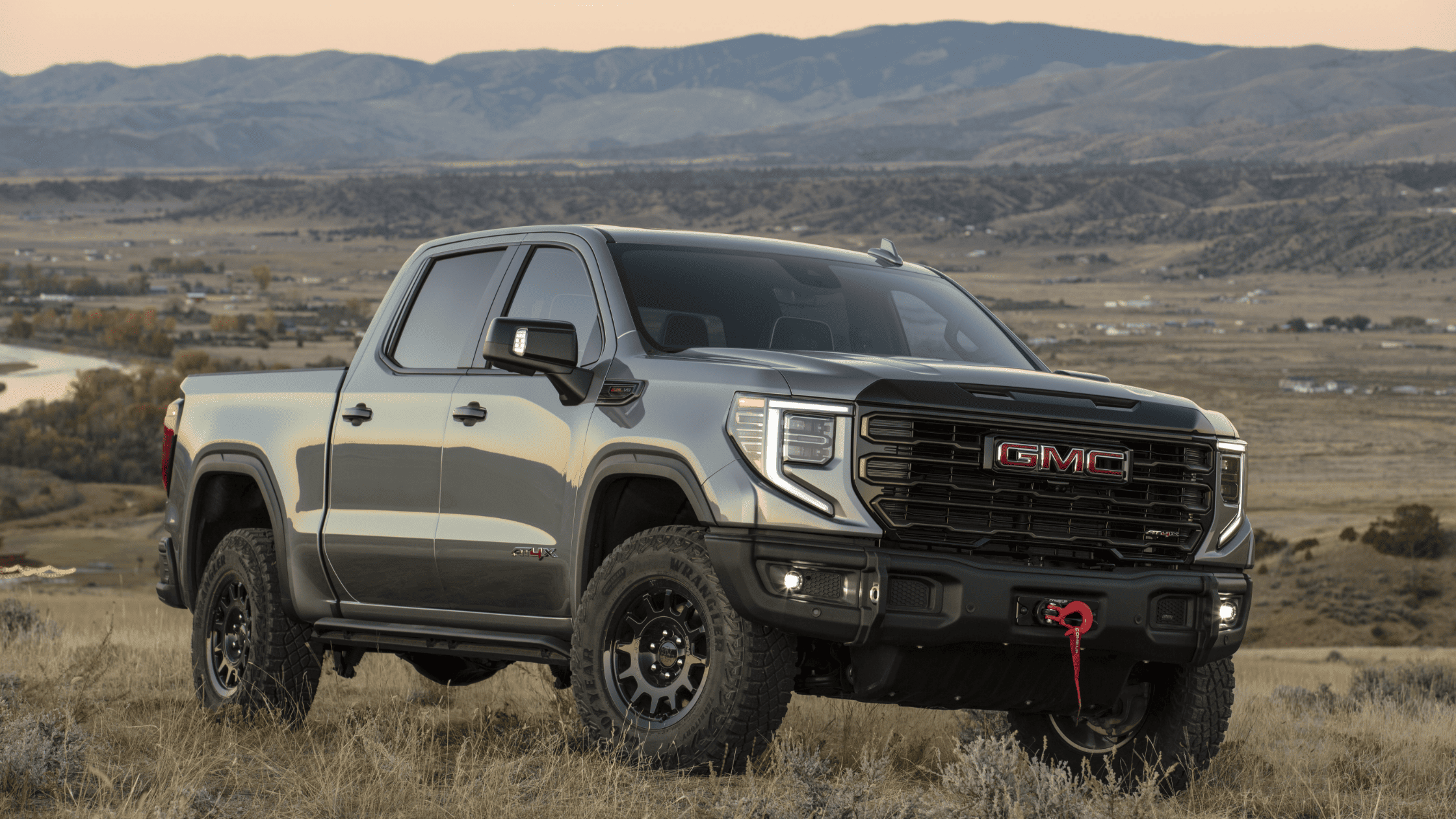 2024 GMC Sierra 1500 AT4X parked in an open field with rugged off-road tires.