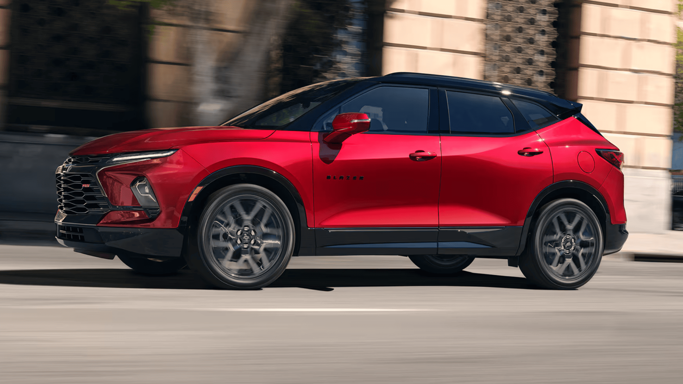 2025 Chevy Blazer RS driving on city street in vibrant red finish