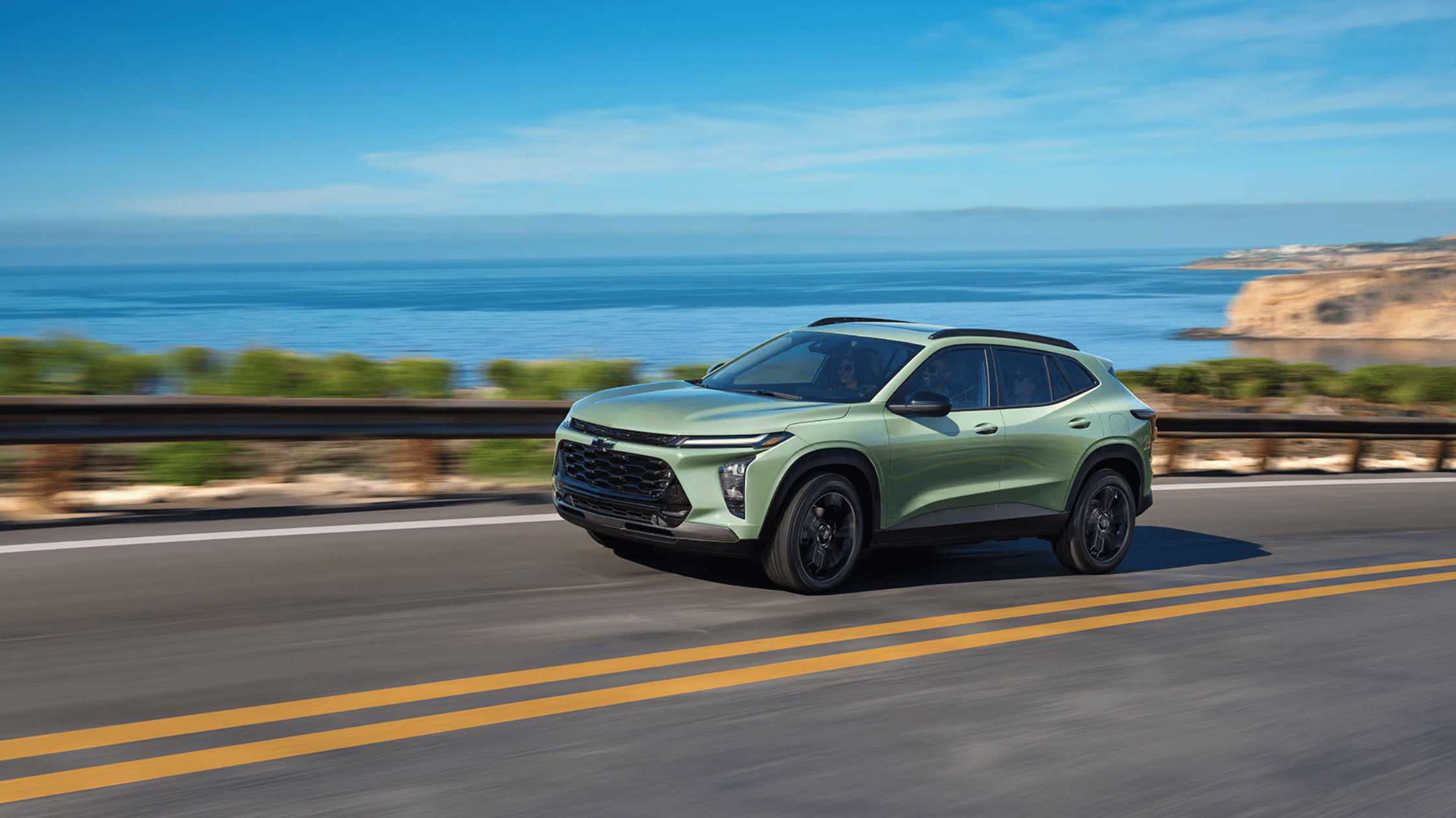Front exterior of the 2025 Chevrolet Trax driving through Morganton, NC, showcasing compact SUV styling and bold body lines.