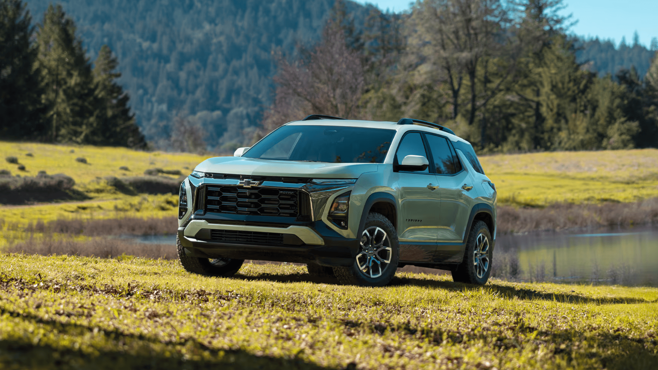 2025 Chevrolet Equinox parked by a pond near West Jefferson, NC, with scenic forest and mountain backdrop
