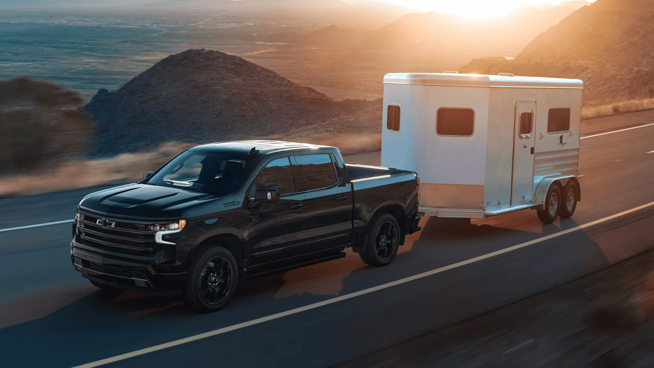 2025 Chevrolet Silverado on the move towing a trailer along the scenic highways of West Jefferson, North Carolina