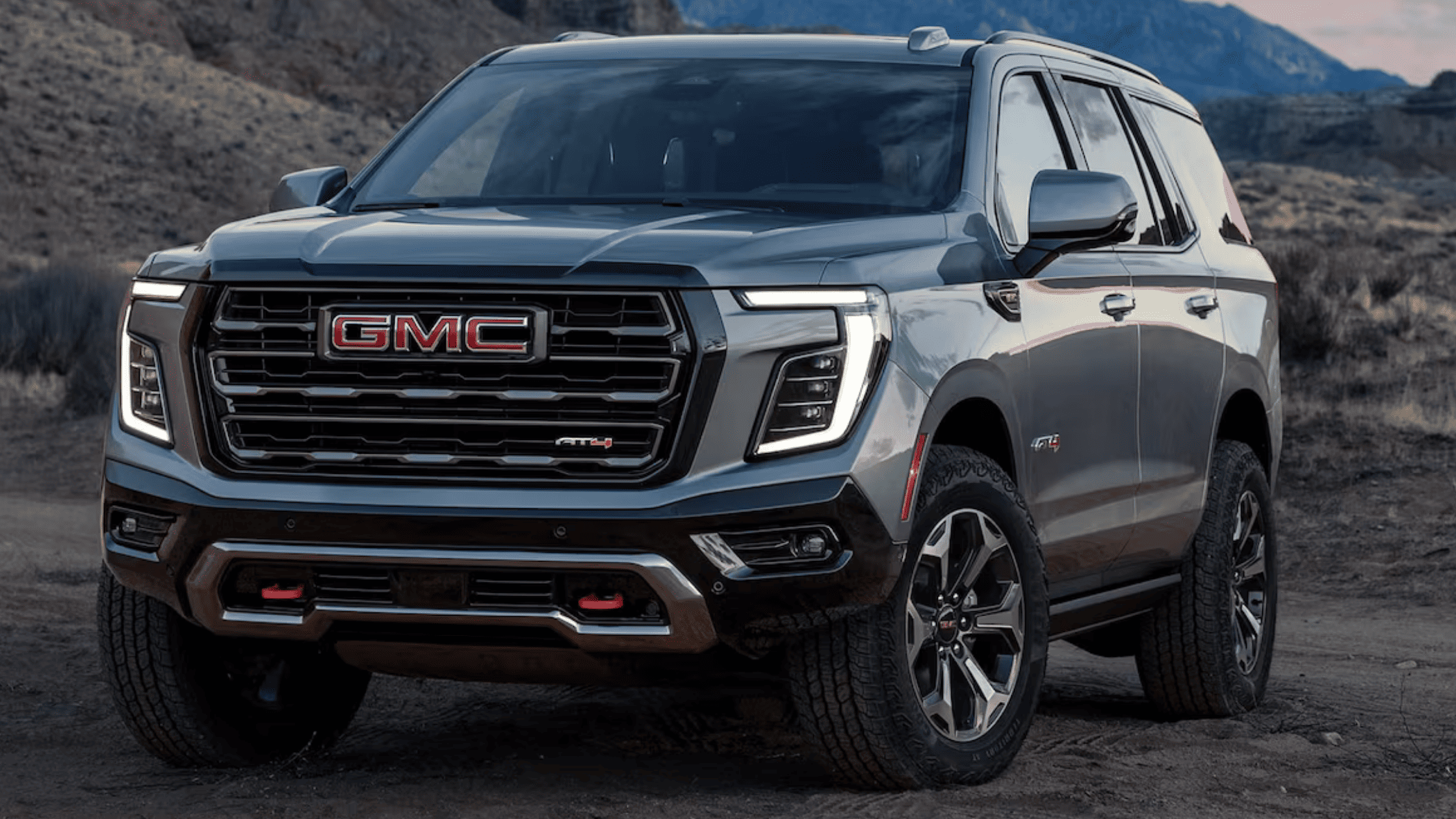 2025 GMC Yukon AT4 front grille and LED headlights in mountain terrain