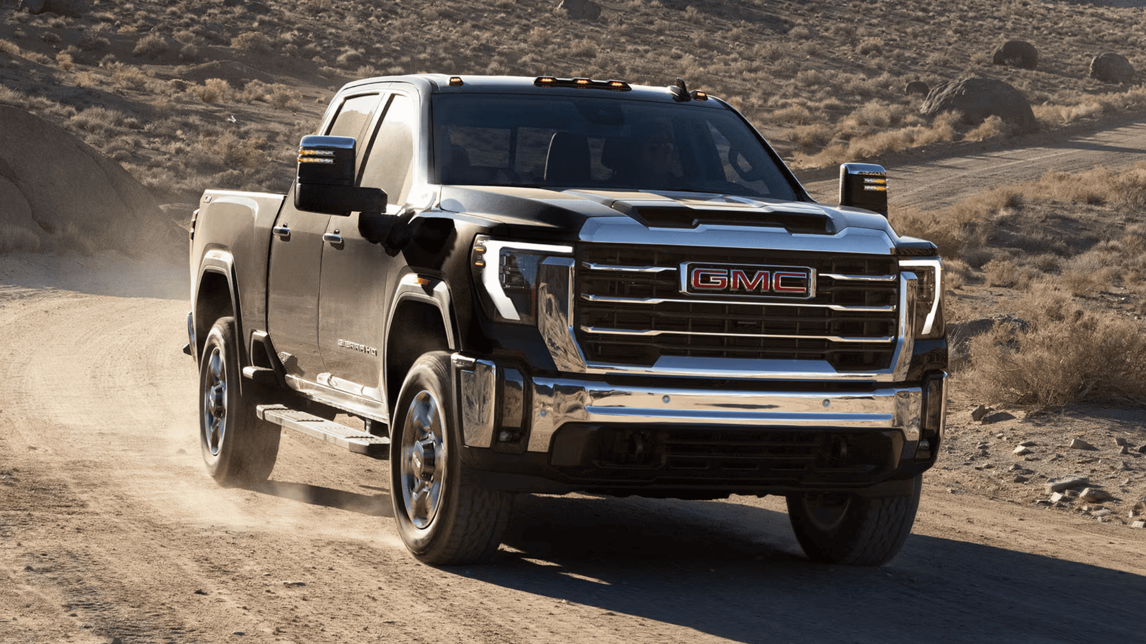 2025 GMC Sierra 2500 heavy-duty truck driving in Morganton NC, showcasing powerful grille and stance.
