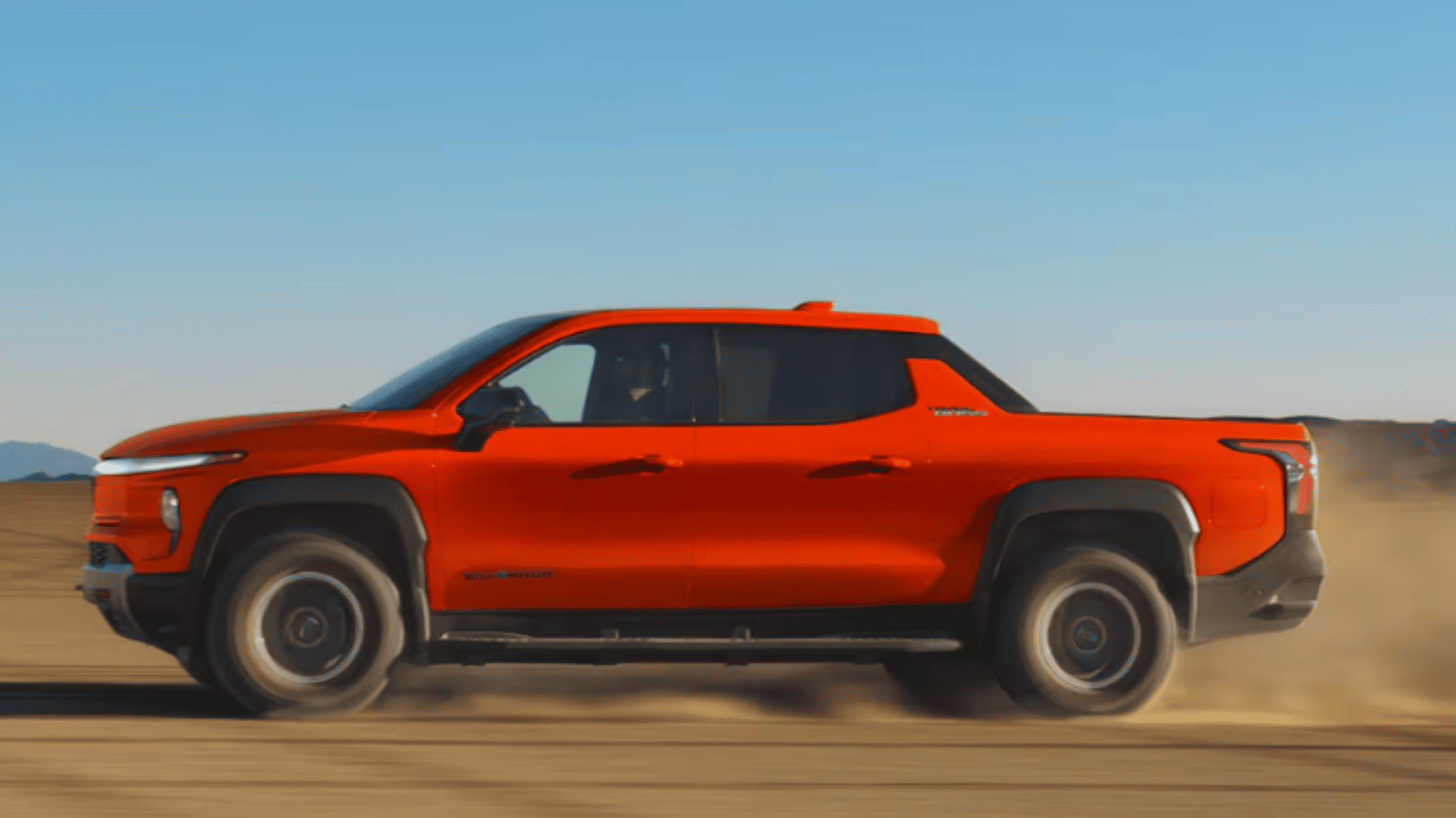 2026 Chevrolet Silverado EV driving on open terrain near Morganton, NC, highlighting its bold electric truck design, four-door cab, and rugged capability.