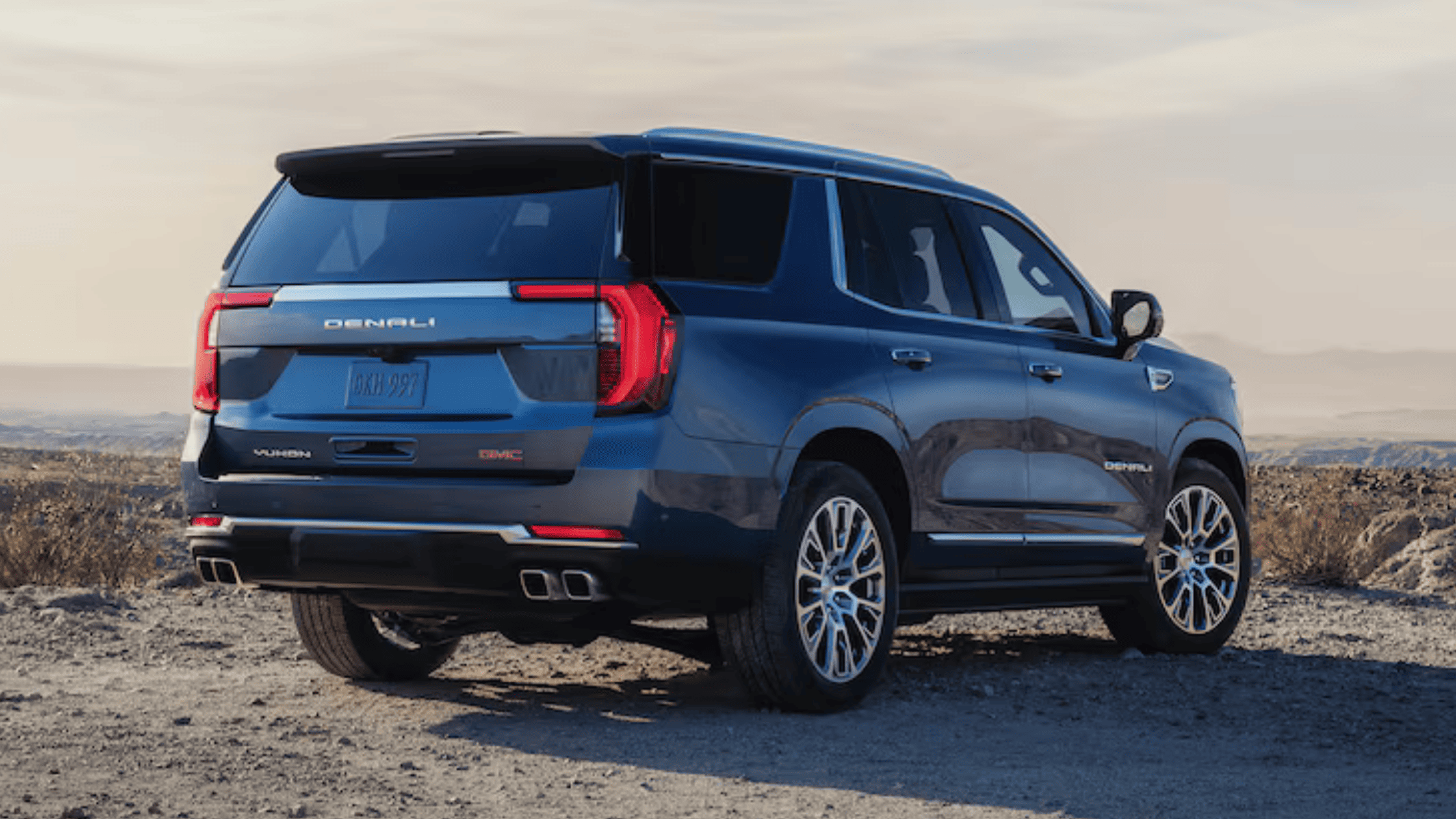 2026 GMC Yukon XL Denali parked on rugged terrain near Morganton, NC, showcasing rear exterior design, LED taillights, and premium SUV styling.