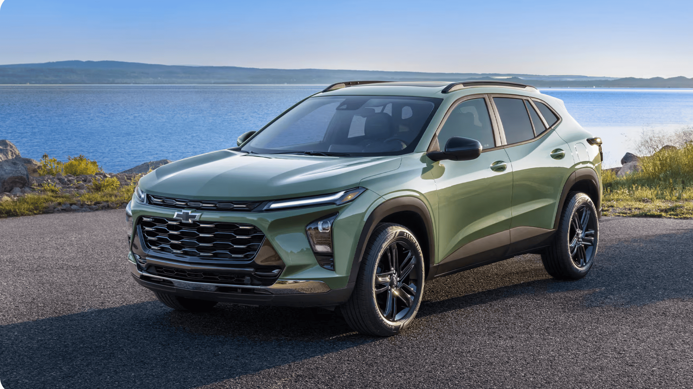 Green 2026 Chevrolet Trax parked near a scenic waterfront in Boone, NC, highlighting compact SUV styling and modern design.