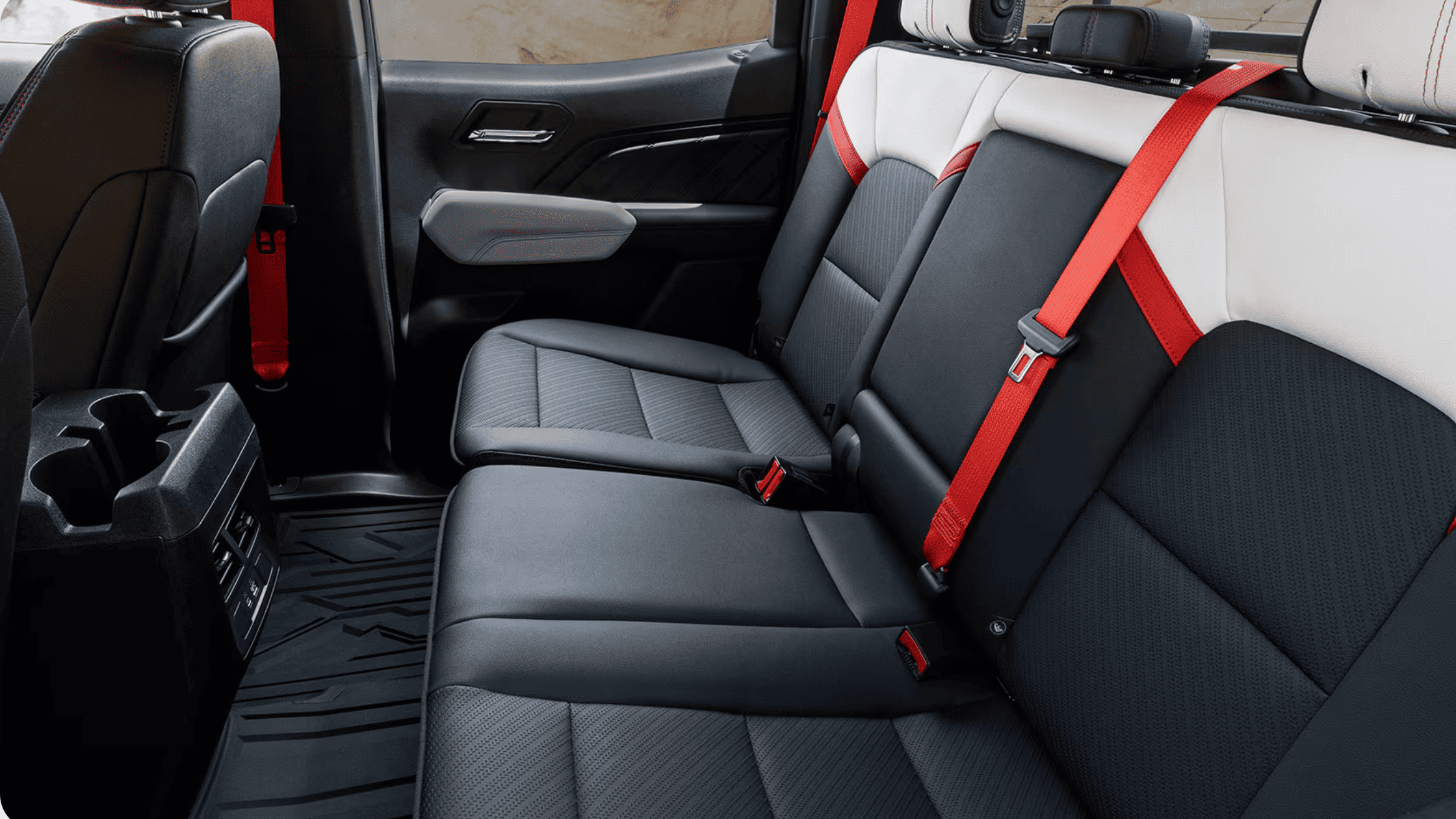 Rear seating area of the 2026 GMC Canyon showing spacious cabin layout, premium materials, and red seatbelt accents.