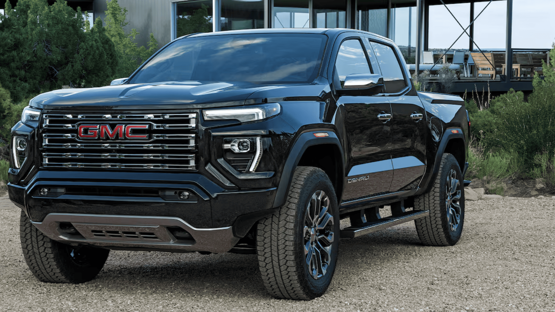 2026 GMC Canyon Denali in black with chrome grille parked on a gravel surface in Boone, NC.