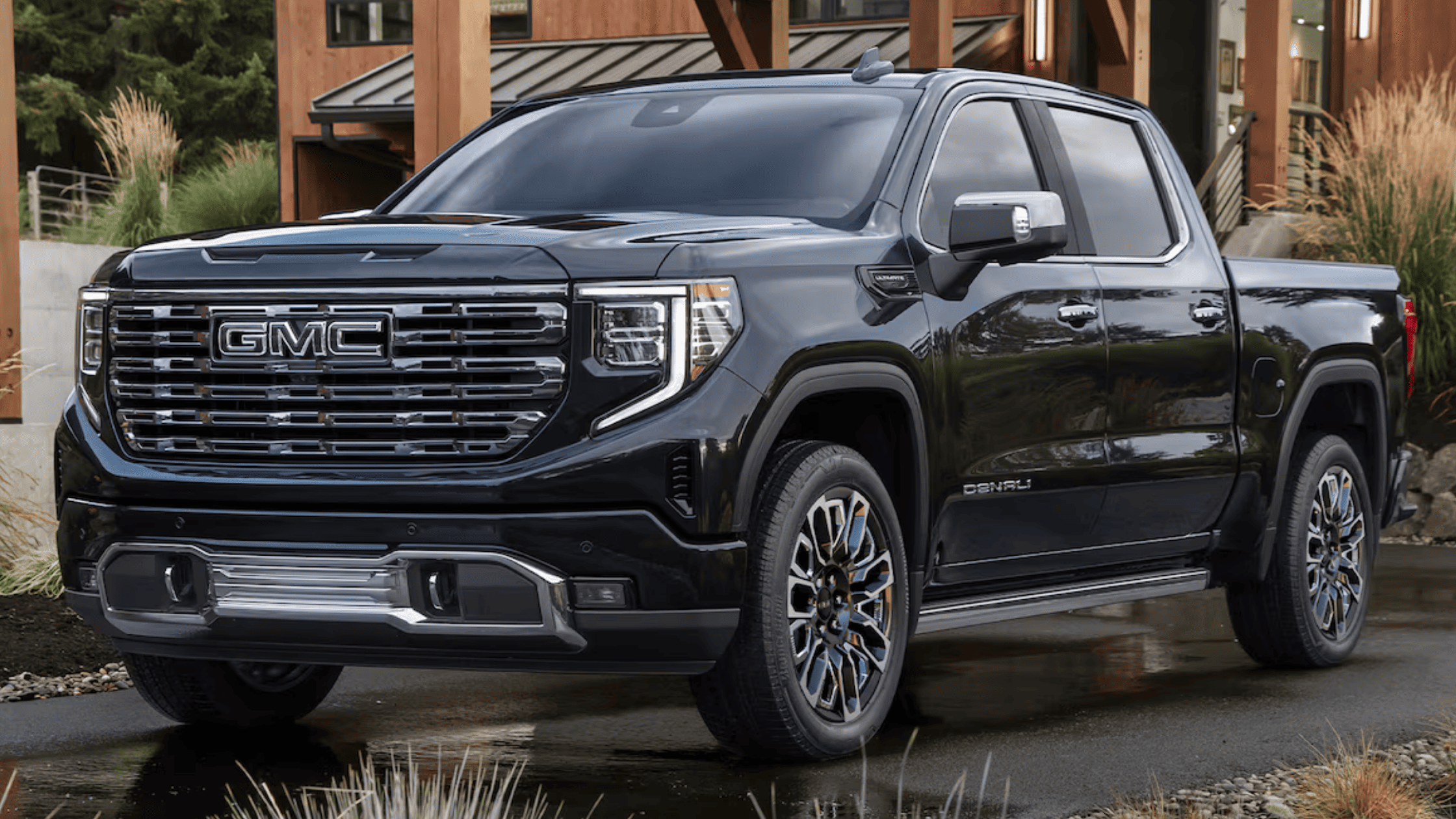 2026 GMC Sierra 1500 Denali in black with chrome grille parked outside a modern building in Boone, NC.